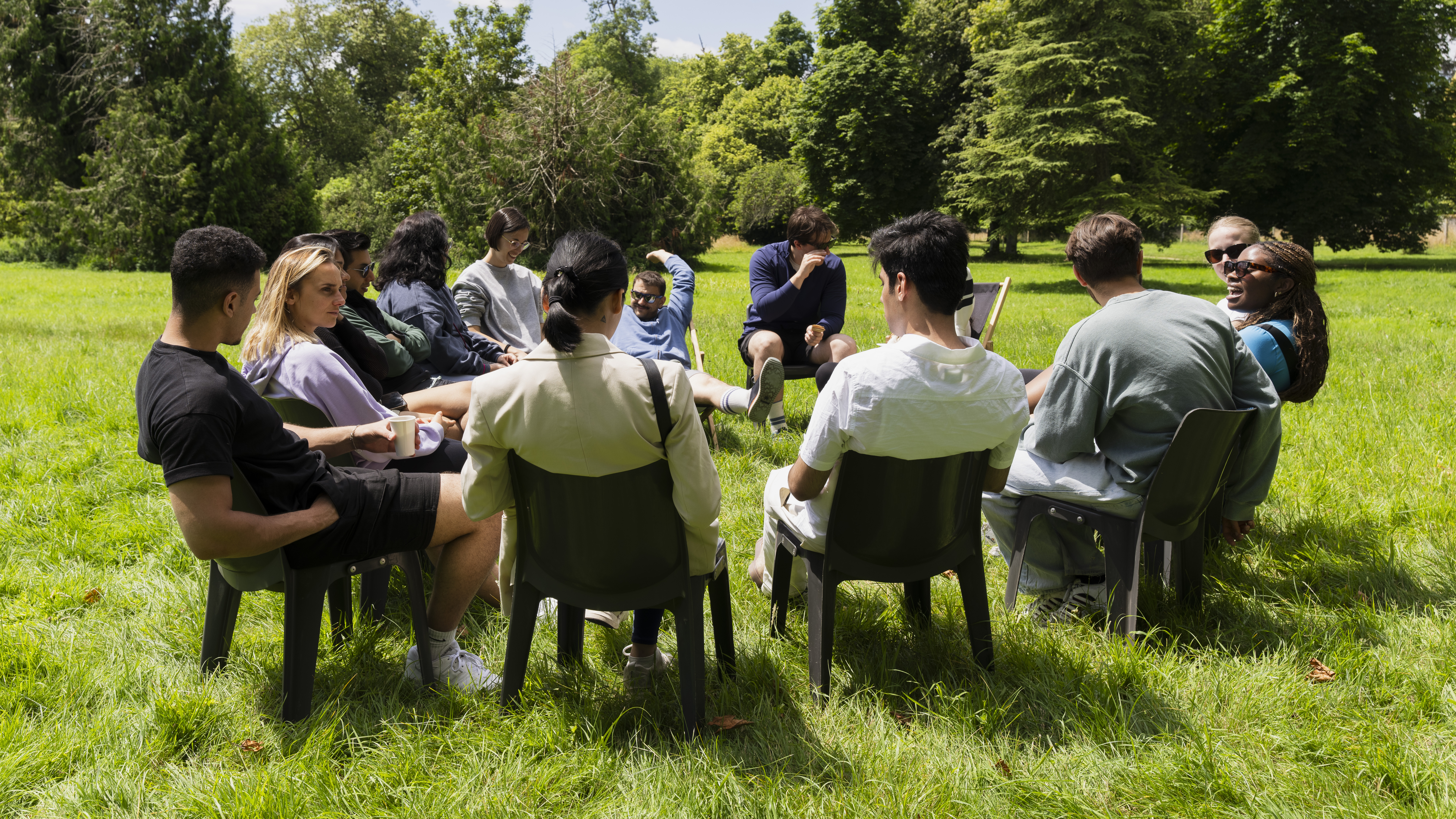 Un groupe de collaborateurs assis en cercle sur des chaises dans un parc