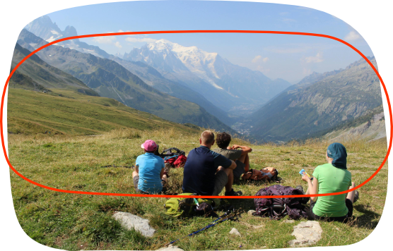 un groupe assis sur l'herbe contemple une chaine de montagne
